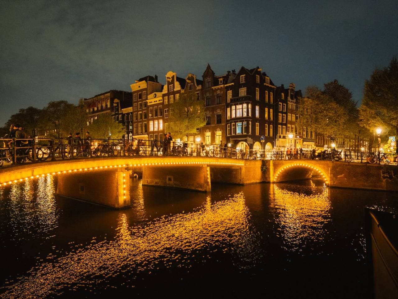 A bridge lit with lights over a canal at night